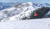 A skiier on a snowfiled at Deer Valley with a snow covered mountain backdrop