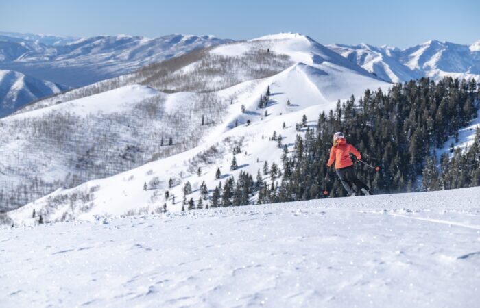 A skiier on a snowfiled at Deer Valley with a snow covered mountain backdrop