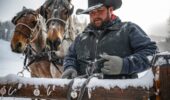 A man tying two horses to a wooden fence at Deer Valley