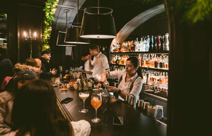 Guests sitting at the bar in the living room of Hotel Jerome, Aspen USA