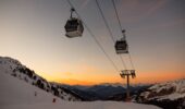 Ski chairlift over snow-covered mountains at sunset in Méribel, France.
