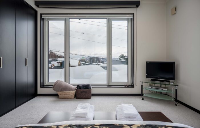 Bedroom with snowy window views at Shochikubai accommodation Furano