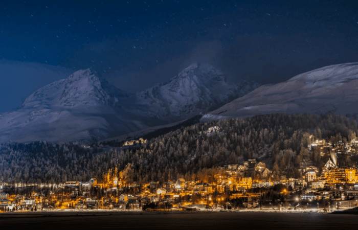 Night view of St. Moritz village illuminated in the Swiss Alps during winter.