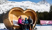 Family posing in the iconic heart seat in Méribel, France during a winter ski holiday.
