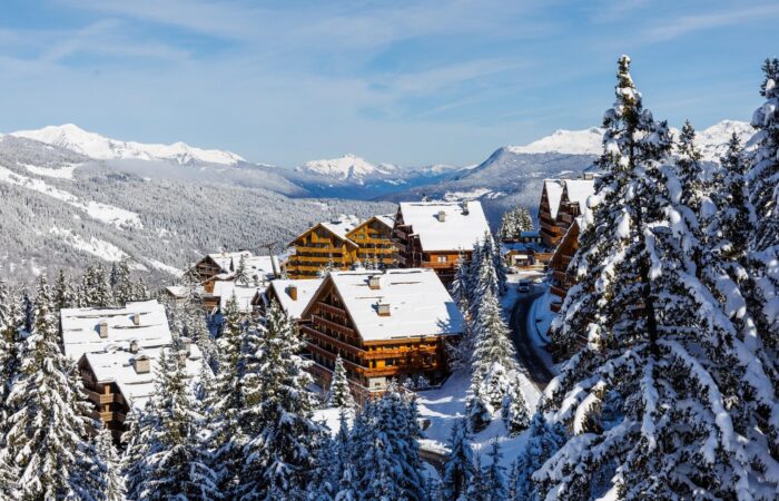 Snow-covered alpine lodge buildings in Méribel, France during winter.