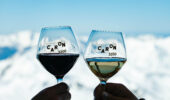 Two wine glasses clinking in front of a snow covered mountain at Val Thorens France