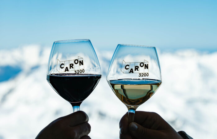 Two wine glasses clinking in front of a snow covered mountain at Val Thorens France