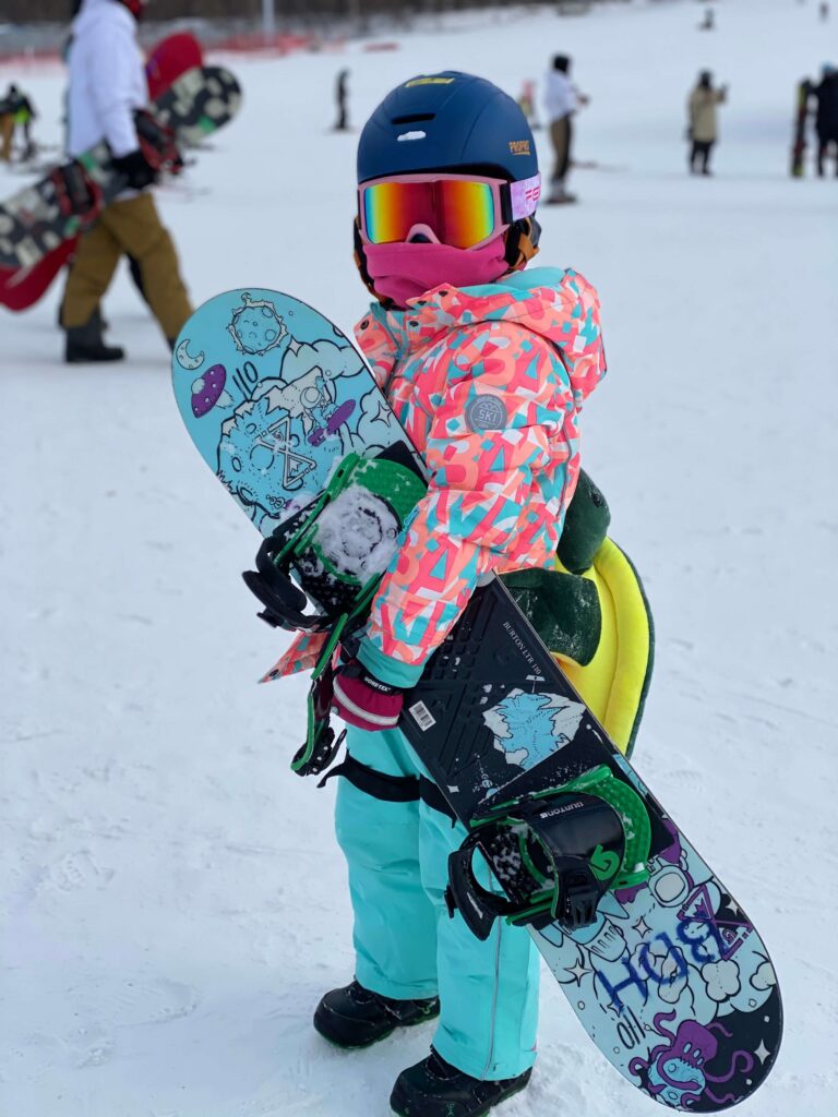 child with snowboard at Club Med Beidahu
