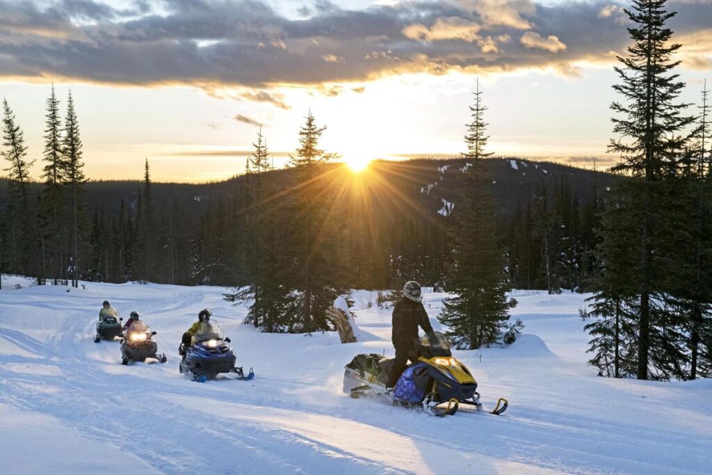 holiday makers riding snowmobiles at Sun Peaks ski resort.