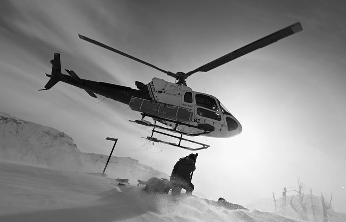 A heli skiier being dropped at a snow covered mountain top