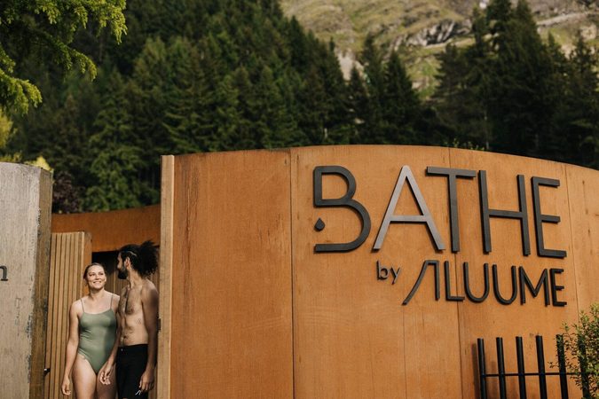 Two clients standing beside the Bathe by Aluume Queenstown sign