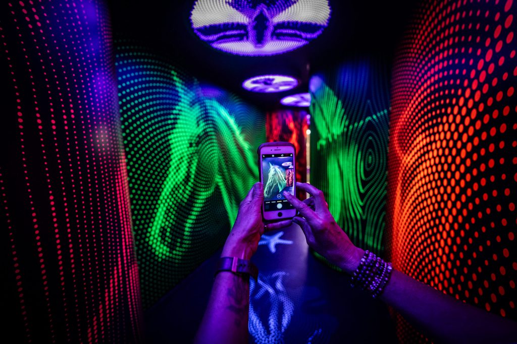 Hands holding a phone taking a photo of bright lights in a dark room