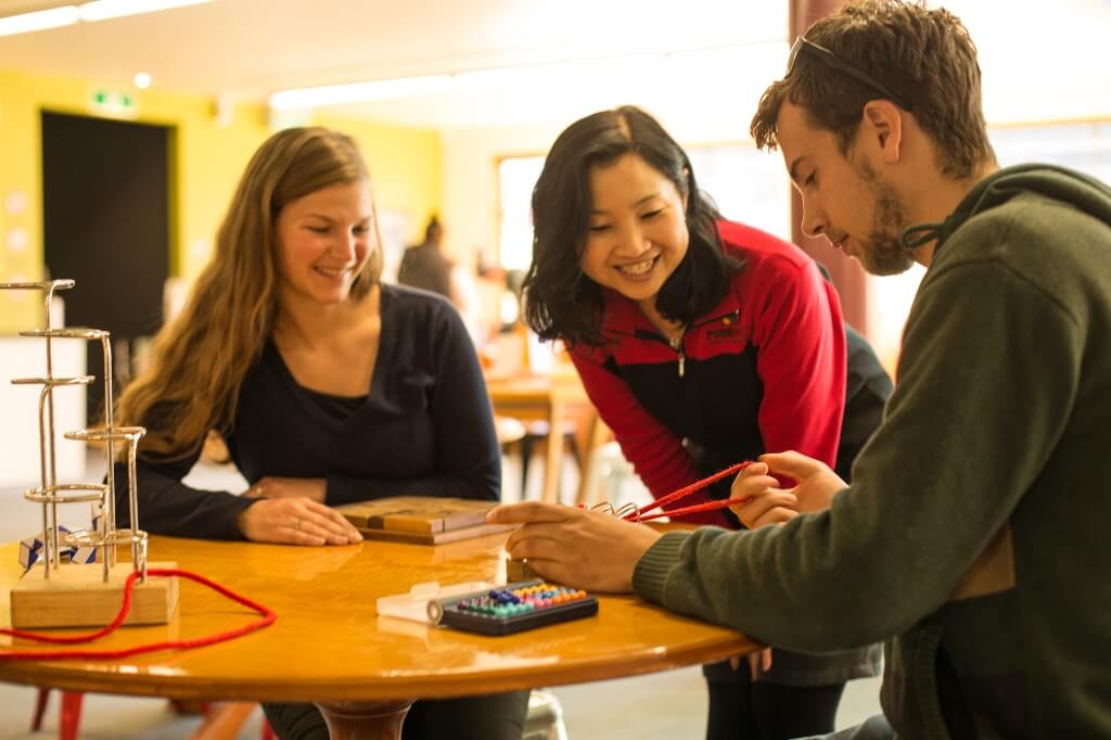 A group of three people working on a puzzle at the puzzle centre at Puzzling World