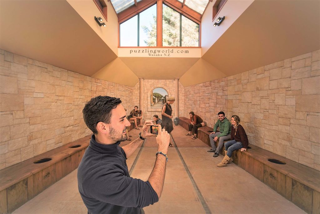 A man taking a photo of a couple at the Roman Toilets at Puzzling World